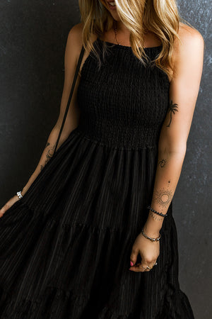Black tiered maxi dress with textured smocked bodice and thin straps.