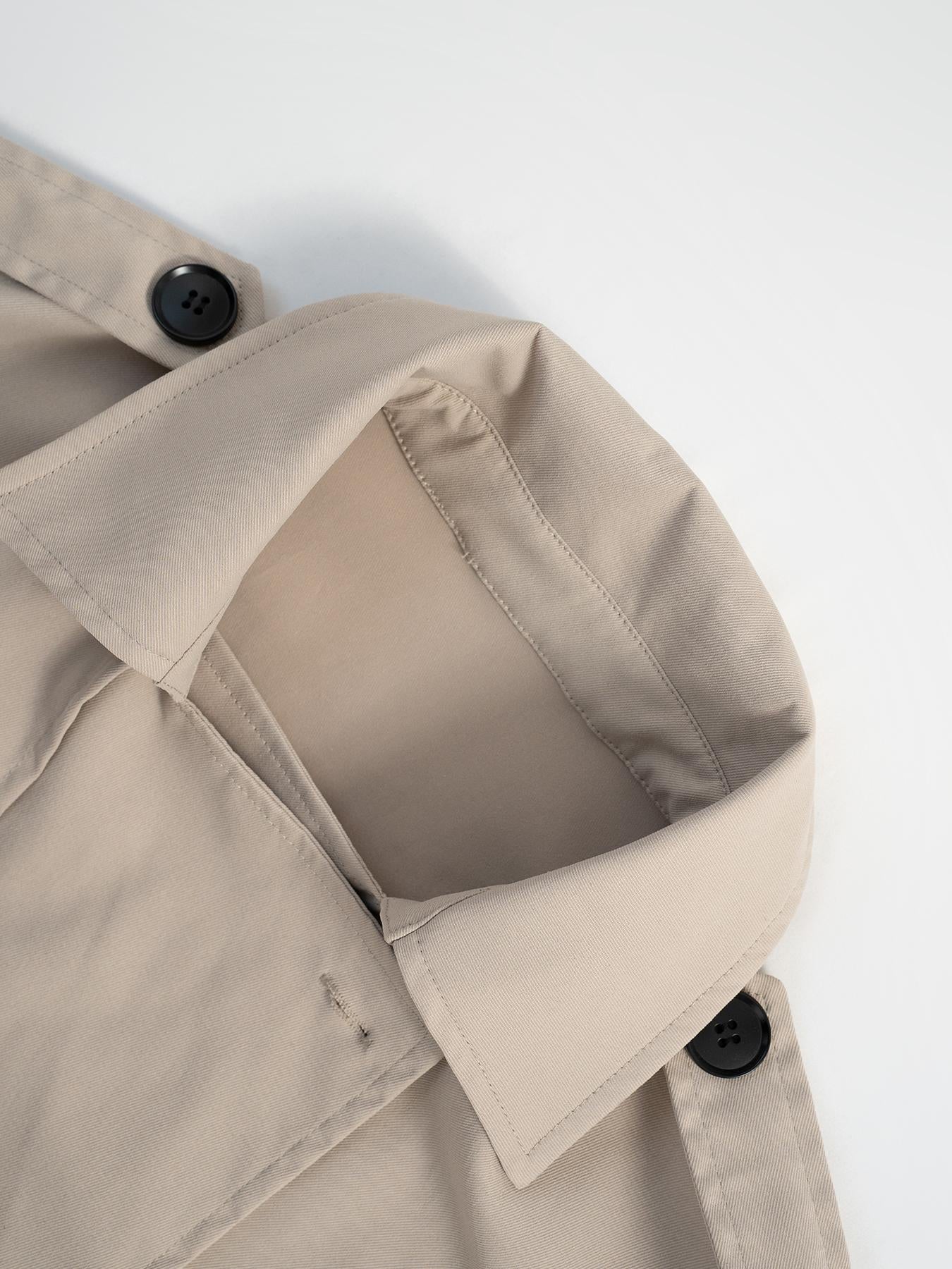 Beige cropped double-breasted trench coat with button details and classic collar.