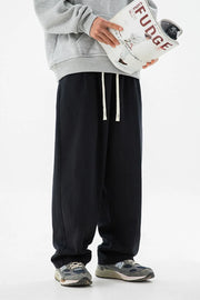 Black wide-leg trousers with drawstring and pleats, styled with a grey hoodie.