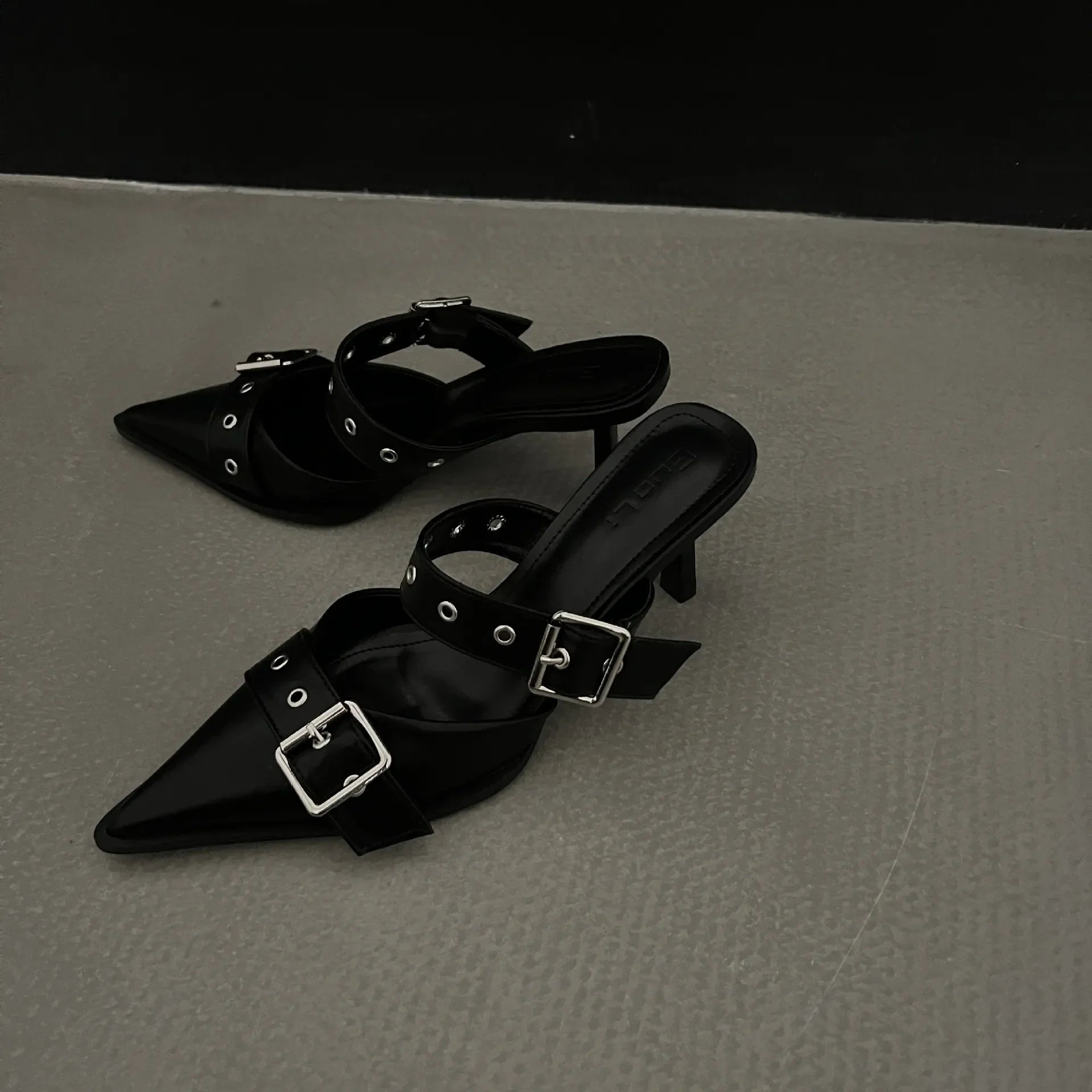 Black pointed buckle mules with silver hardware and double straps.