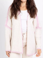 Cream oversized cardigan with contrast pink trim and textured sleeves.