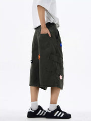 Dark gray cotton cargo shorts with floral appliques and wide legs.