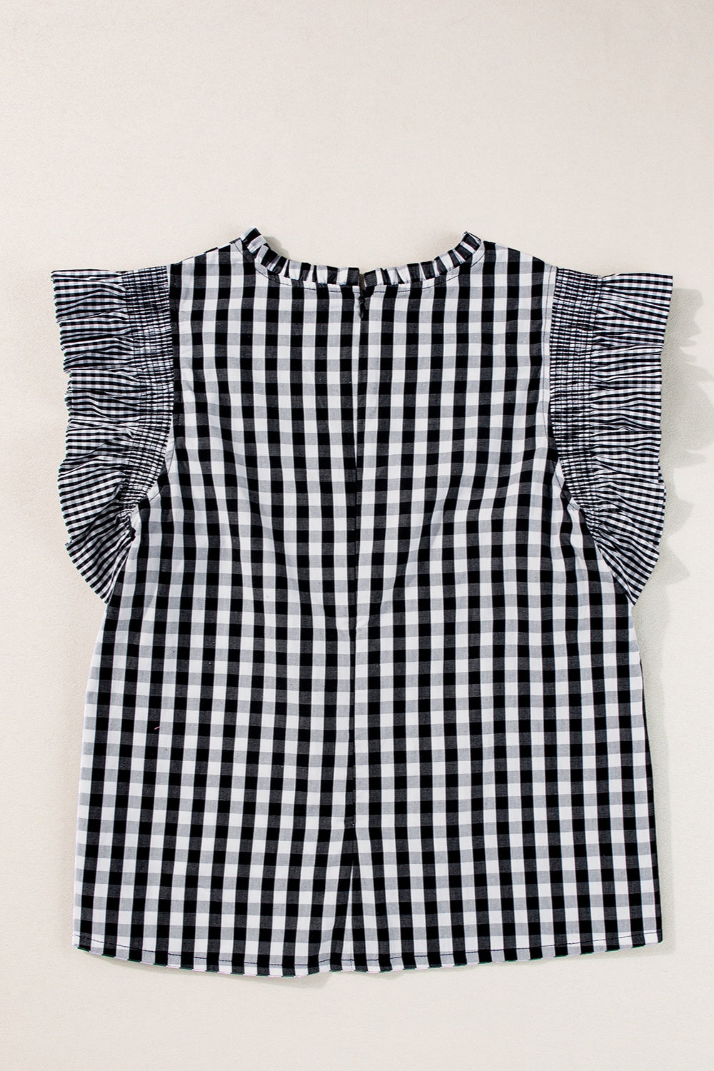 Black gingham blouse with mock neck and ruffled cap sleeves.