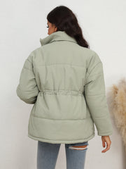 Light green textured puffer jacket with drawstring waist and high collar.