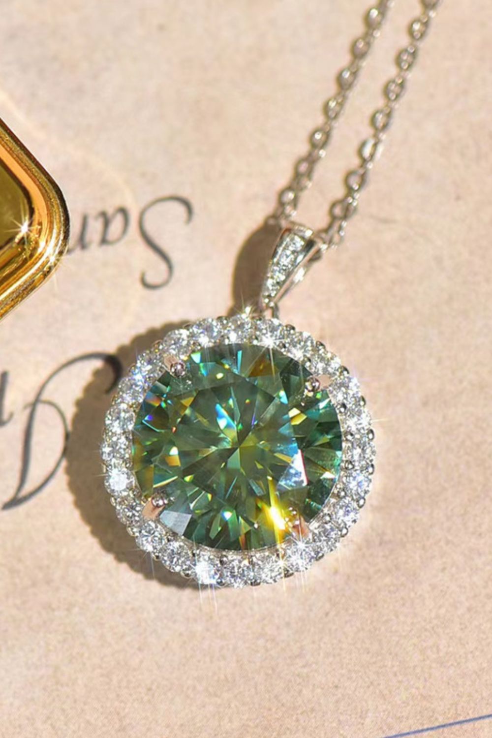 Emerald cut halo moissanite necklace in platinum with a green center stone.