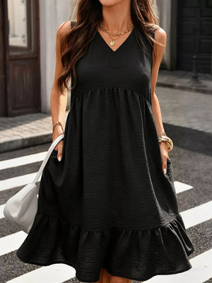 Black V-neck sleeveless ruffle hem dress with textured fabric and pockets.