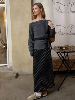 Black polka dot maxi skirt with a belted waist, paired with a grey off-the-shoulder top.