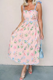 Pink midi dress with wildflower print, blue scalloped trim, and tie straps.