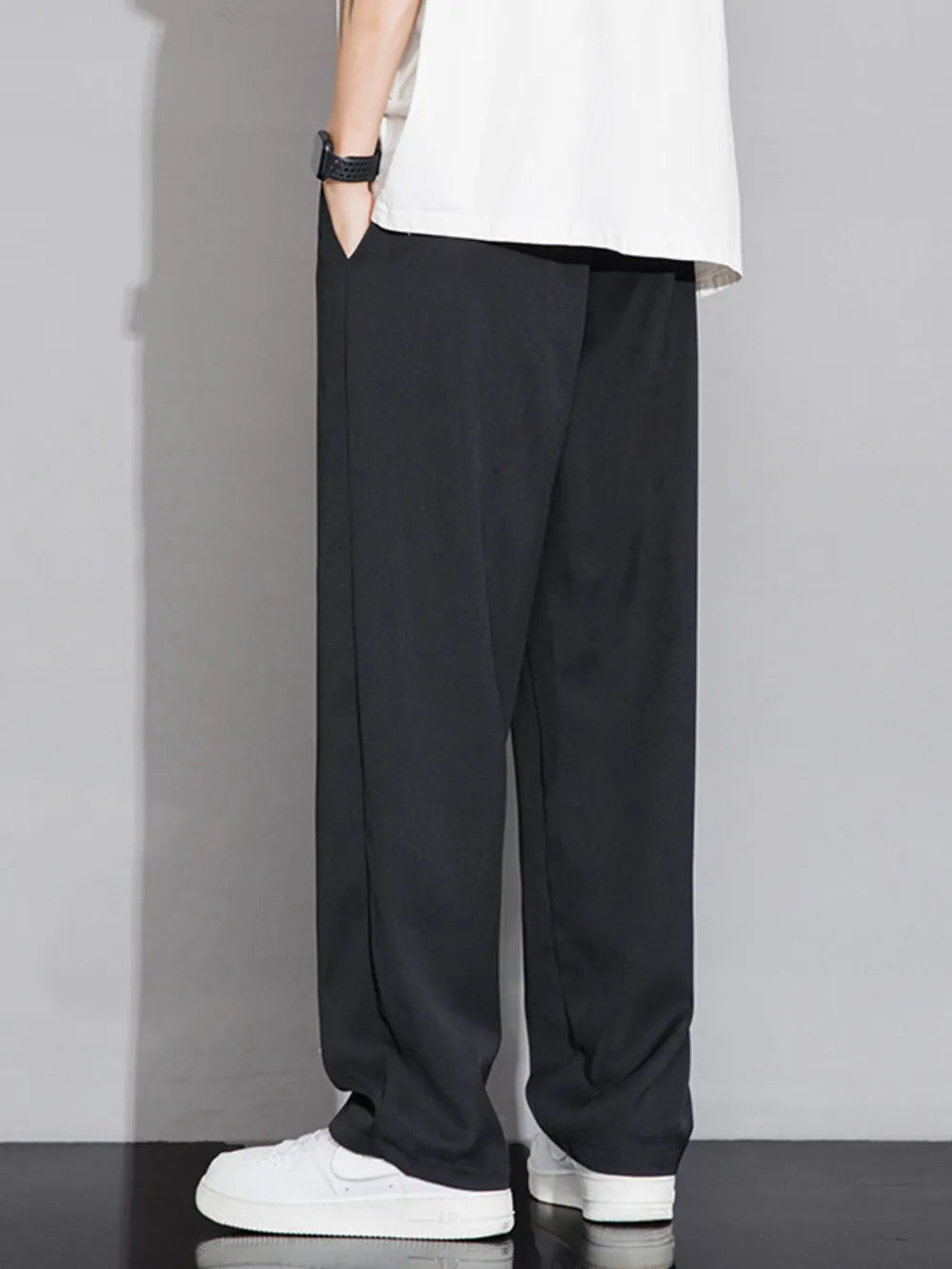 Men's black wide-leg sweatpants with pockets, styled with a white t-shirt and sneakers.