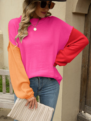 Colorblock drop shoulder knit sweater in hot pink, red, and orange acrylic with a crew neck.