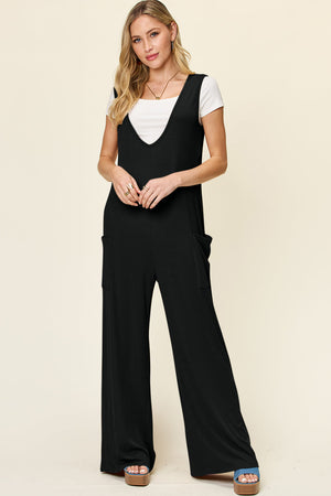 Black wide-leg pocket jumpsuit with deep V-neck, styled with a white tee.