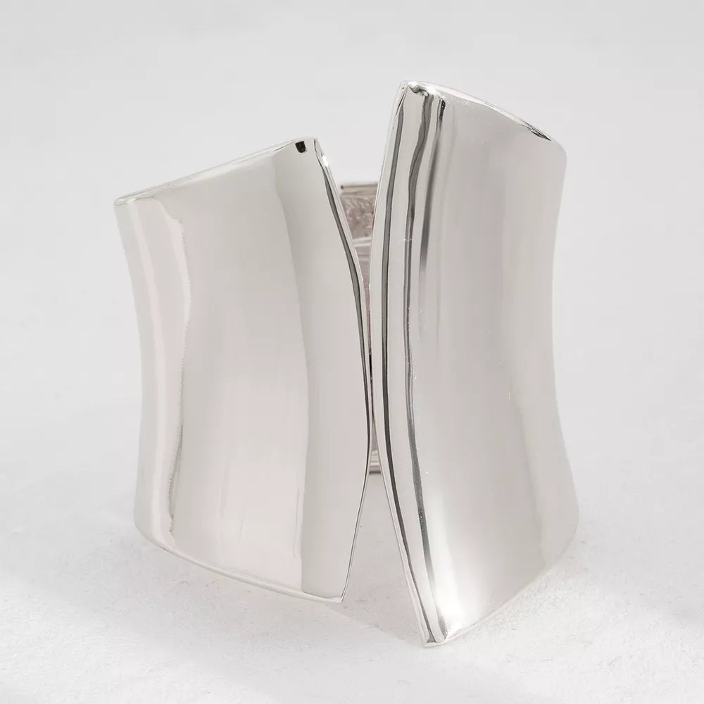 Sculptural silver-toned cuff bracelet with a polished finish and open design.