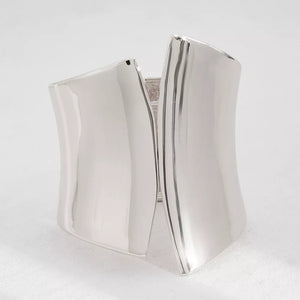 Sculptural silver-toned cuff bracelet with a polished finish and open design.