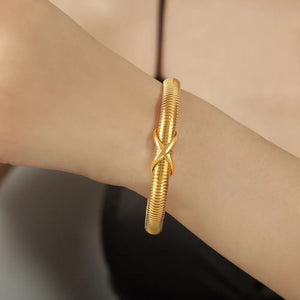 Gold ribbed bangle bracelet with X-detail on a woman's wrist