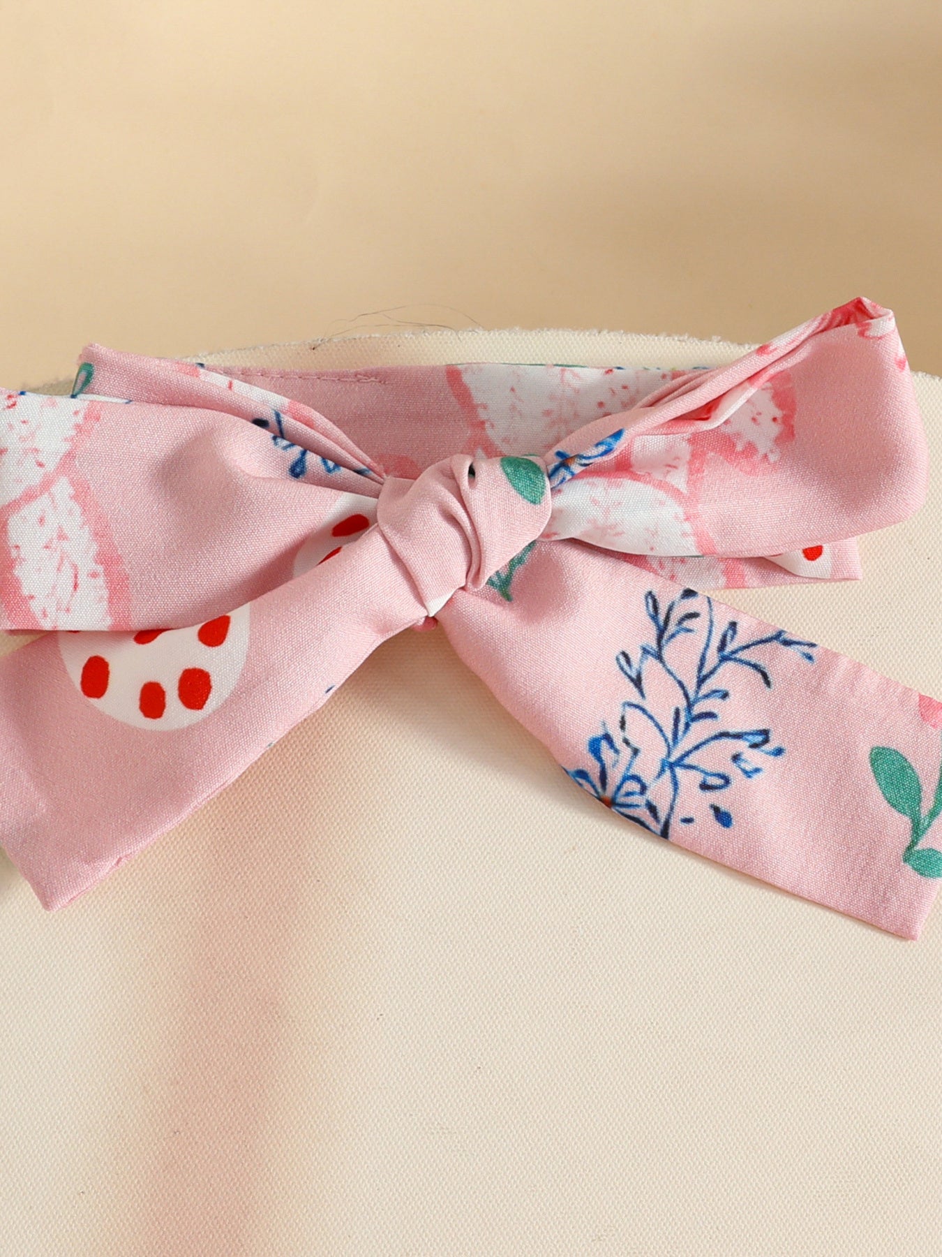 Pink baby headband with bunny and floral print, tied bow detail.