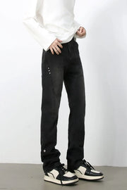 Dark denim jeans with asymmetric seams and button details.