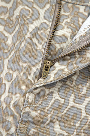 Denim shorts with a grey and beige leopard print and a brass zipper detail.