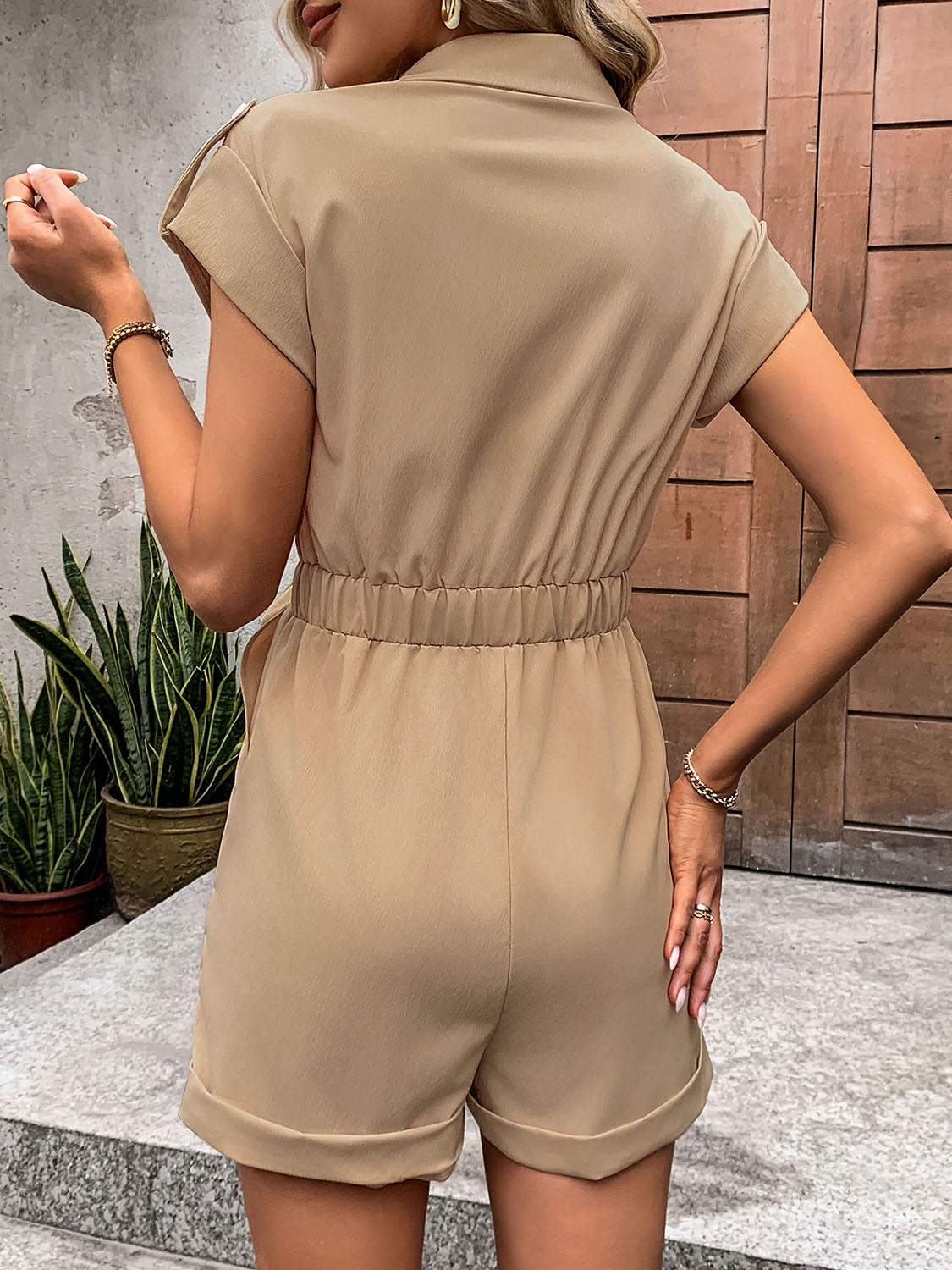 Camel utility romper with tie-waist detail, collared, short sleeves, and cuffed shorts.