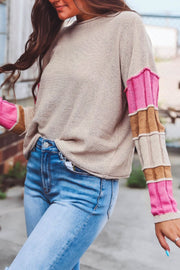 Beige knit sweater with color block sleeves in pink and brown.