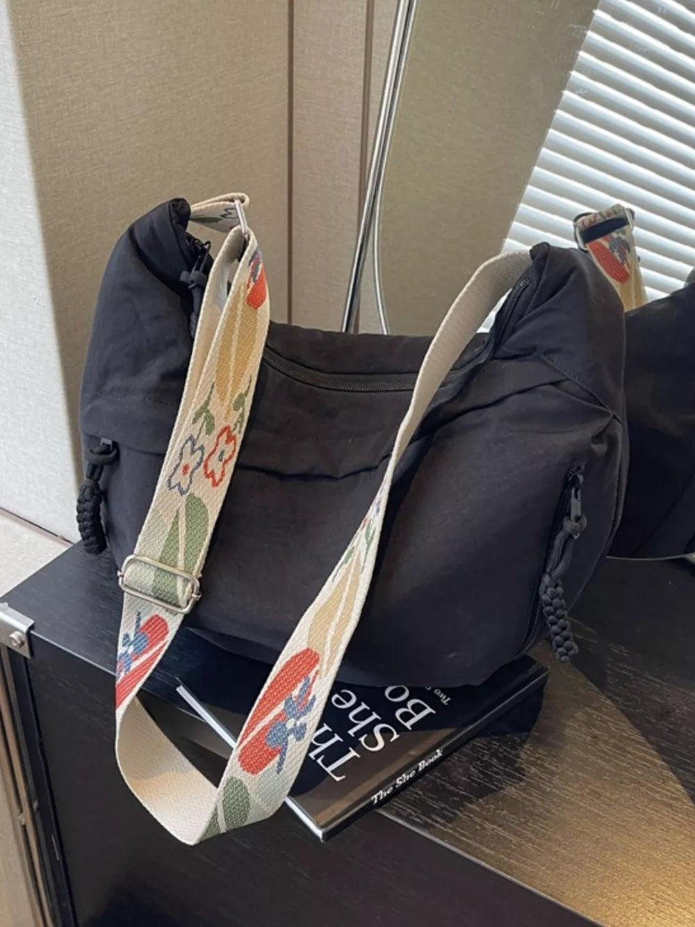 Black crossbody bag with woven floral strap