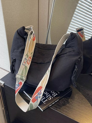 Black crossbody bag with woven floral strap