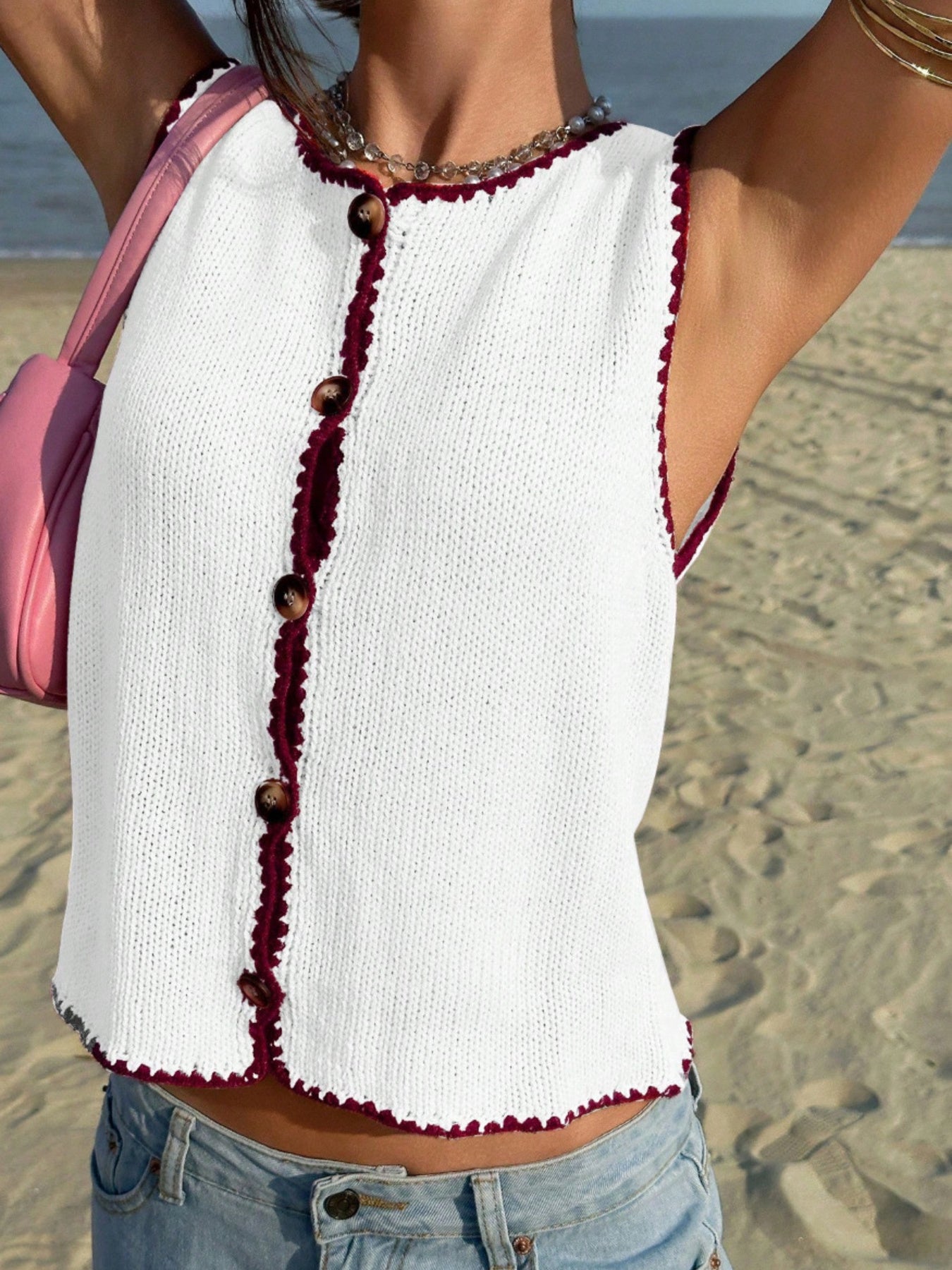 White knit sweater vest with button front and burgundy trim.