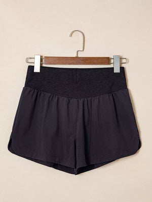 Black athletic jogger shorts with ribbed high-waistband and curved hem