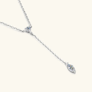 Silver lariat necklace with marquise moissanite pendant and round accent stone.