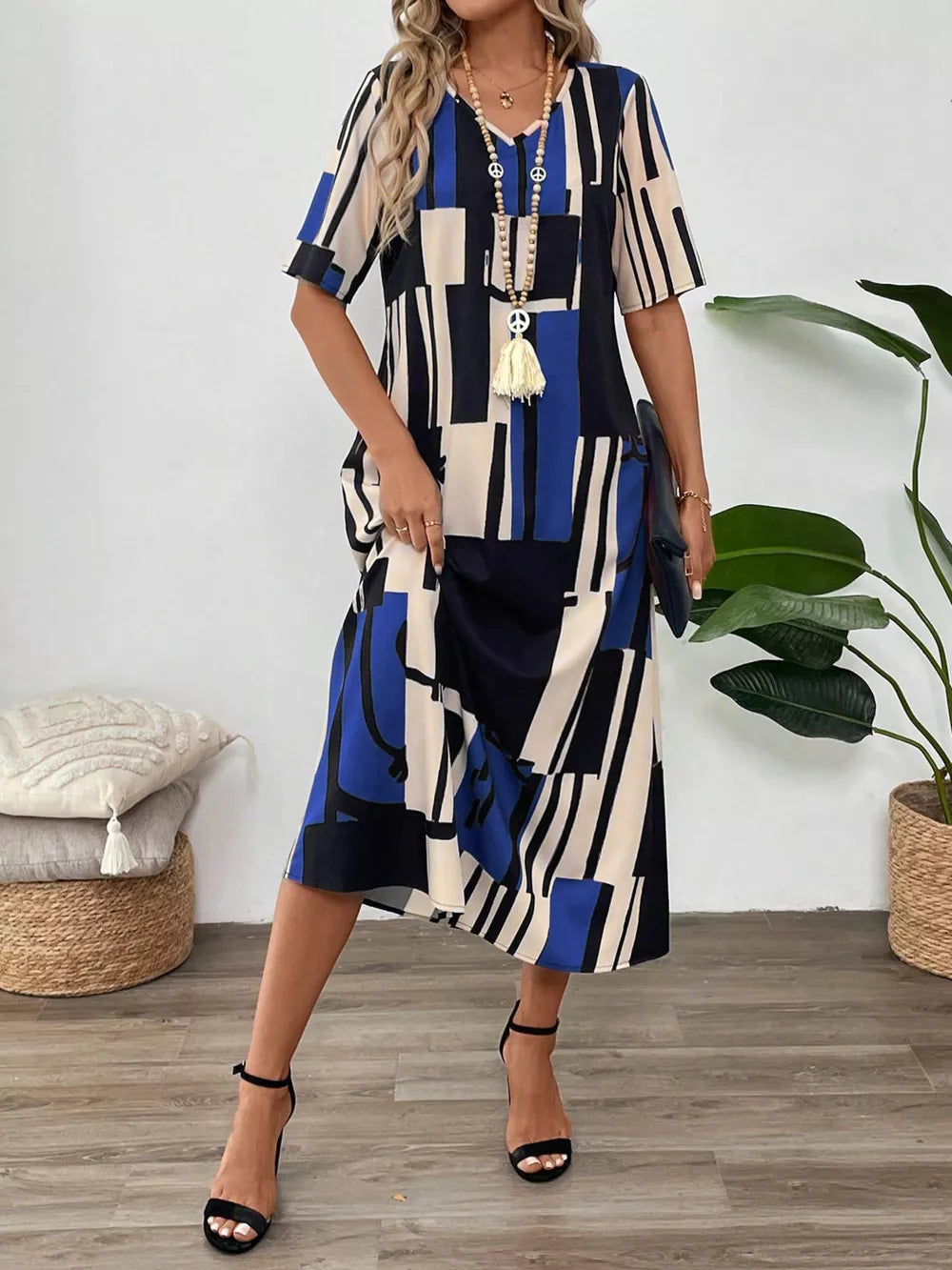 Geometric V-neck midi dress in blue, black, and cream with short sleeves and a relaxed fit.