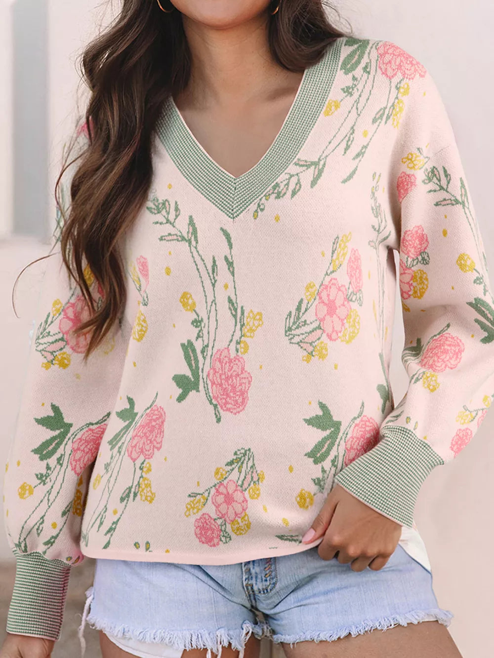Floral v-neck knit sweater with relaxed fit, featuring pink and yellow flowers on a light pink background.