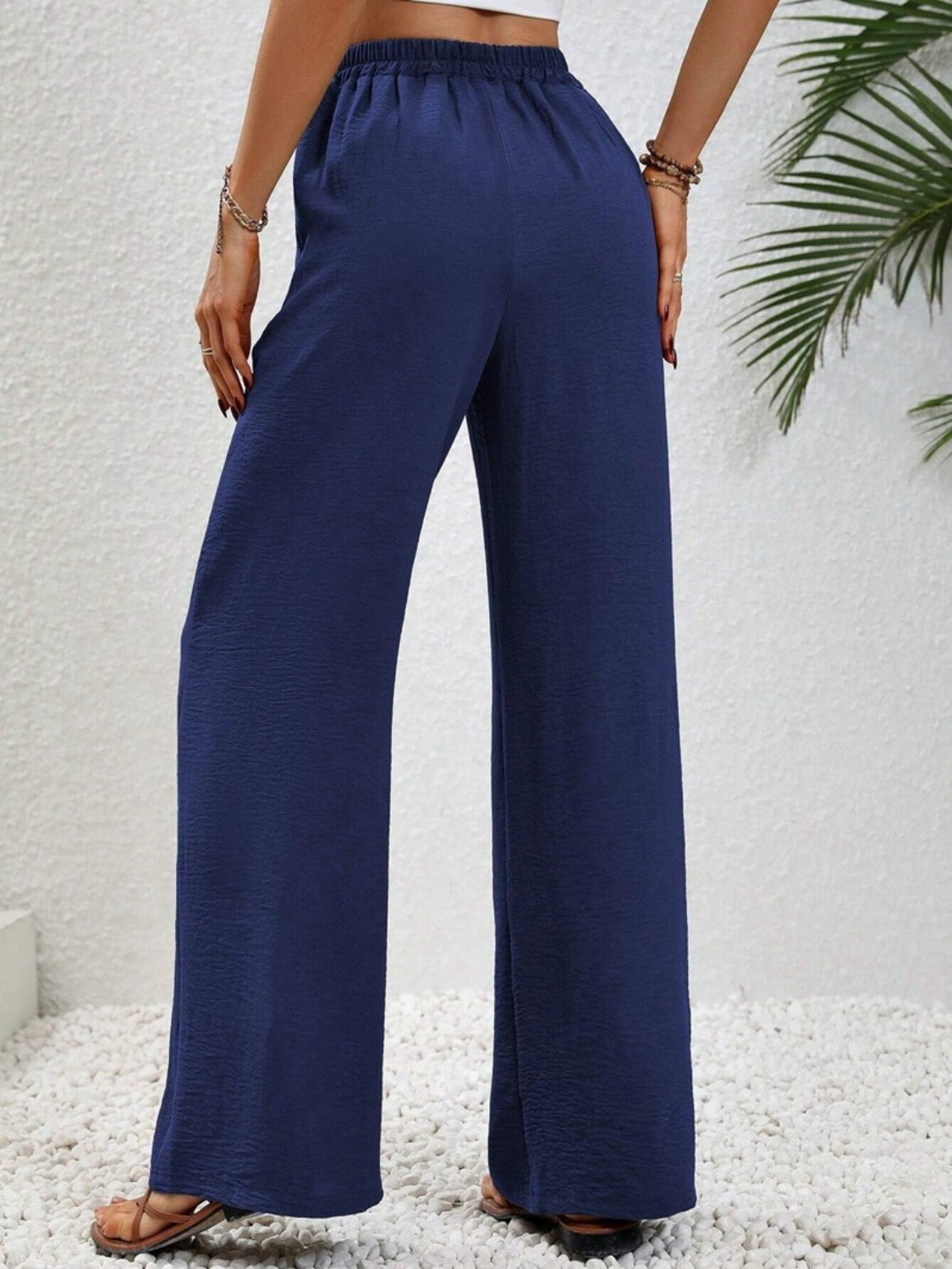 Dark blue textured palazzo trousers with drawstring waist and wide legs.