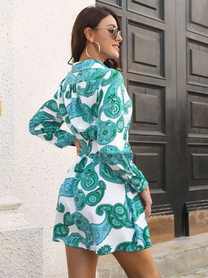 Shirred waist mini dress with paisley print in teal and white, long sleeves, collared neckline.