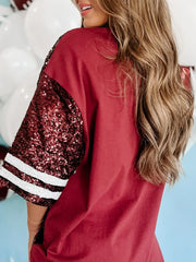 Burgundy oversized tee dress with sequin football graphic sleeves and striped cuffs.