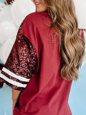 Burgundy oversized tee dress with sequin football graphic sleeves and striped cuffs.