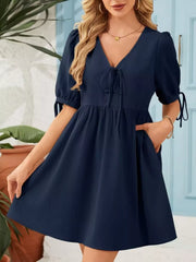 Navy tied neck puff sleeve mini dress with tie details on sleeves and pockets.