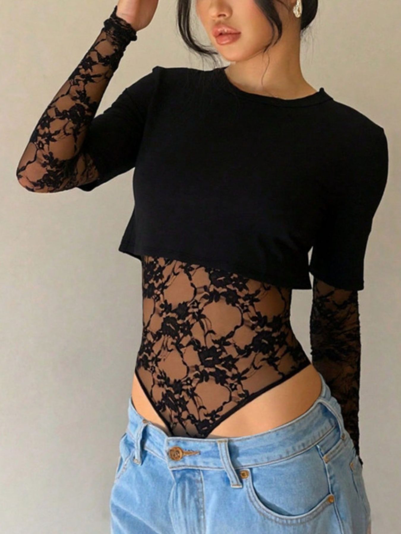 Black lace bodysuit with sheer floral sleeves and torso detail.