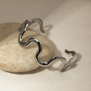 Sculptural ripple cuff bracelet in silver with a wavy, artistic design.