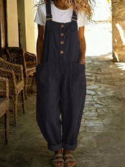 Black wide leg romper with button front, pockets and adjustable straps worn over a white tee.