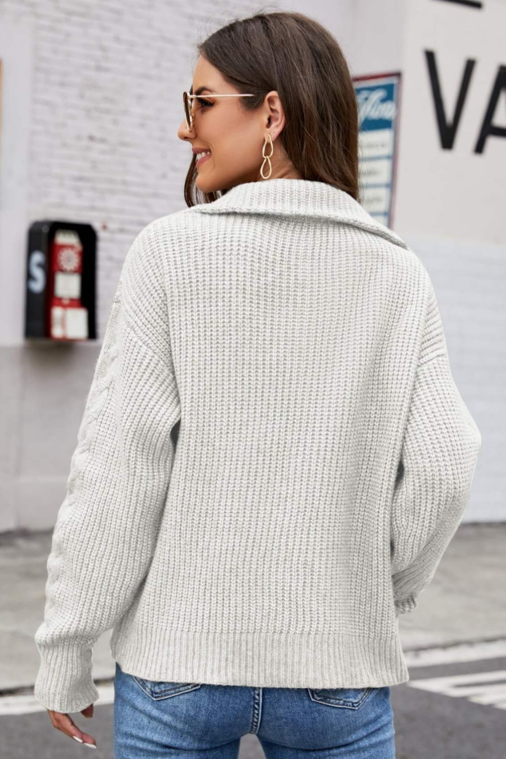 Gray cable knit zip-up sweater with a collar and textured sleeves.
