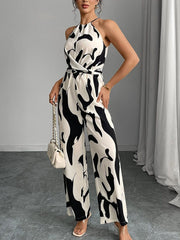 Chic abstract print halter jumpsuit with wrap waist and wide legs.