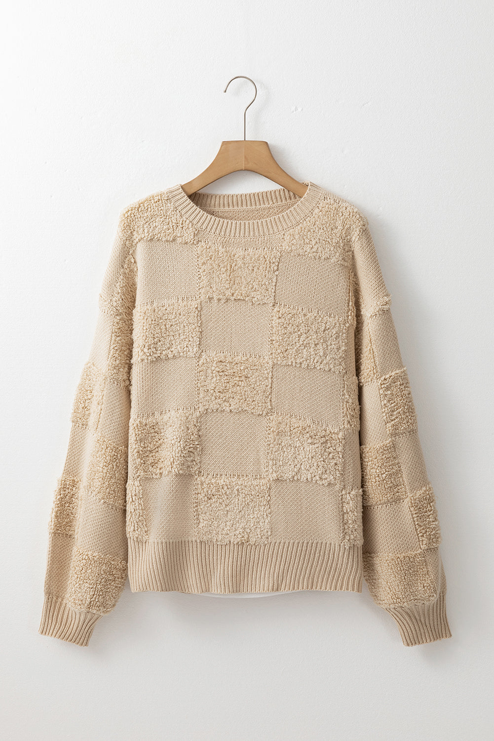 Beige textured checkerboard knit sweater with crewneck and ribbed cuffs and hem.