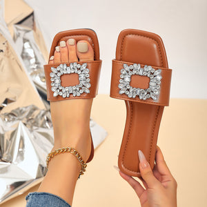 Brown slide sandals with square toe and sparkling rhinestone embellishment.