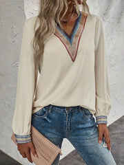 Beige V-neck blouse with colorful embroidered trim on neckline and cuffs.