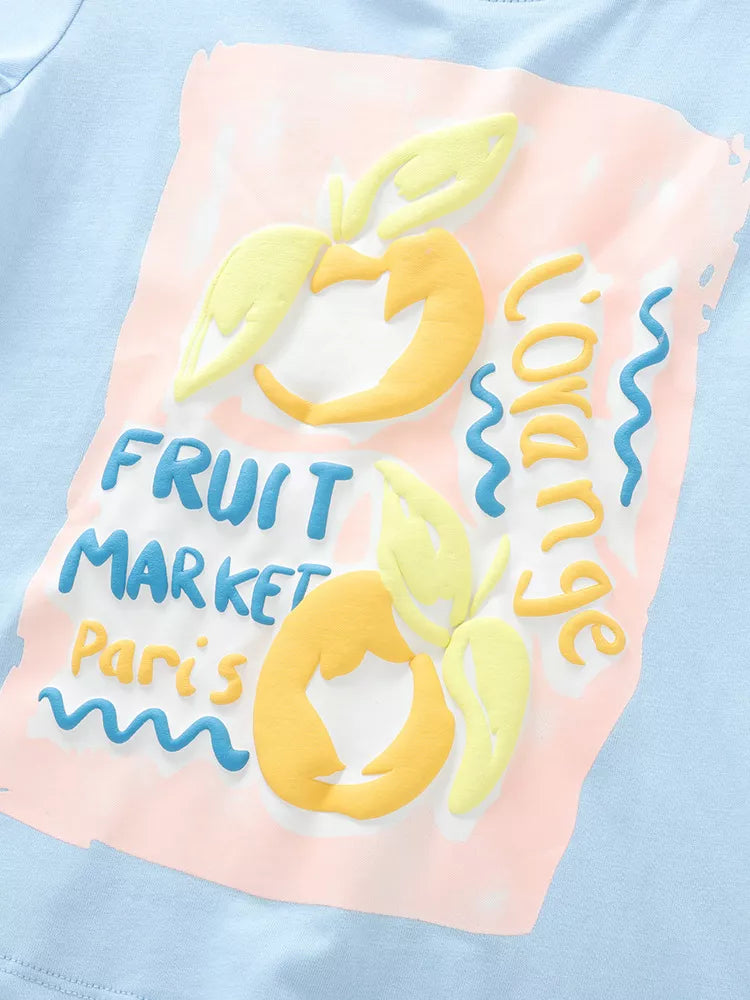 Baby blue cotton tee with playful 3D fruit market graphic and text.