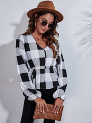 Gingham peplum blouse with gathered waist in black and white plaid, V-neck, long sleeves.