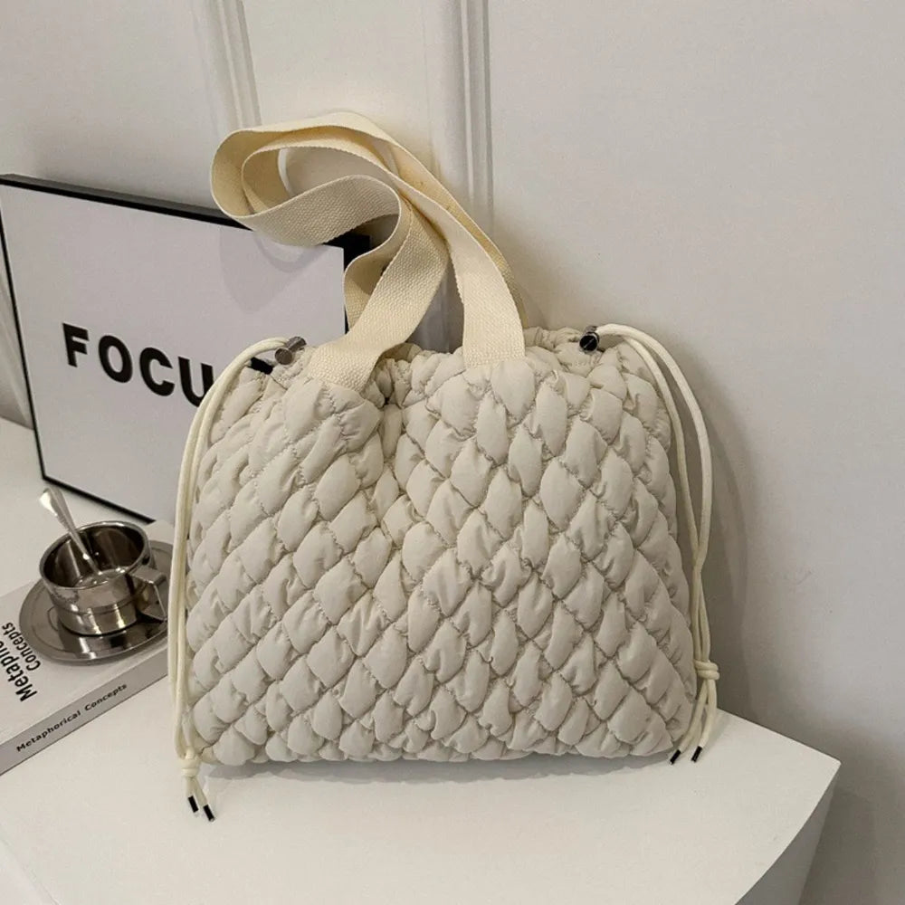 Quilted drawstring carryall handbag in ivory with diamond pattern and canvas straps.