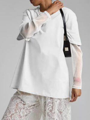 White oversized tee with sheer sparkly sleeves and a black crossbody bag.