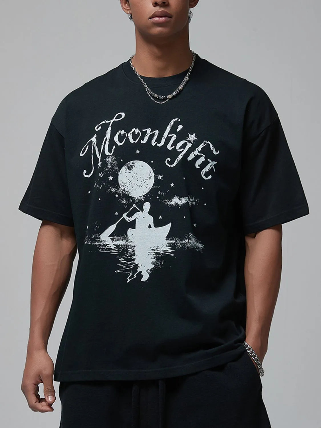 Black oversized tee with white "Moonlight" graphic of a person in a canoe under a moonlit sky.