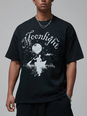 Black oversized tee with white "Moonlight" graphic of a person in a canoe under a moonlit sky.