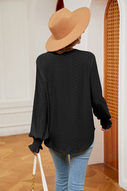 Black eyelet blouse with poet sleeves and ruffled cuffs.
